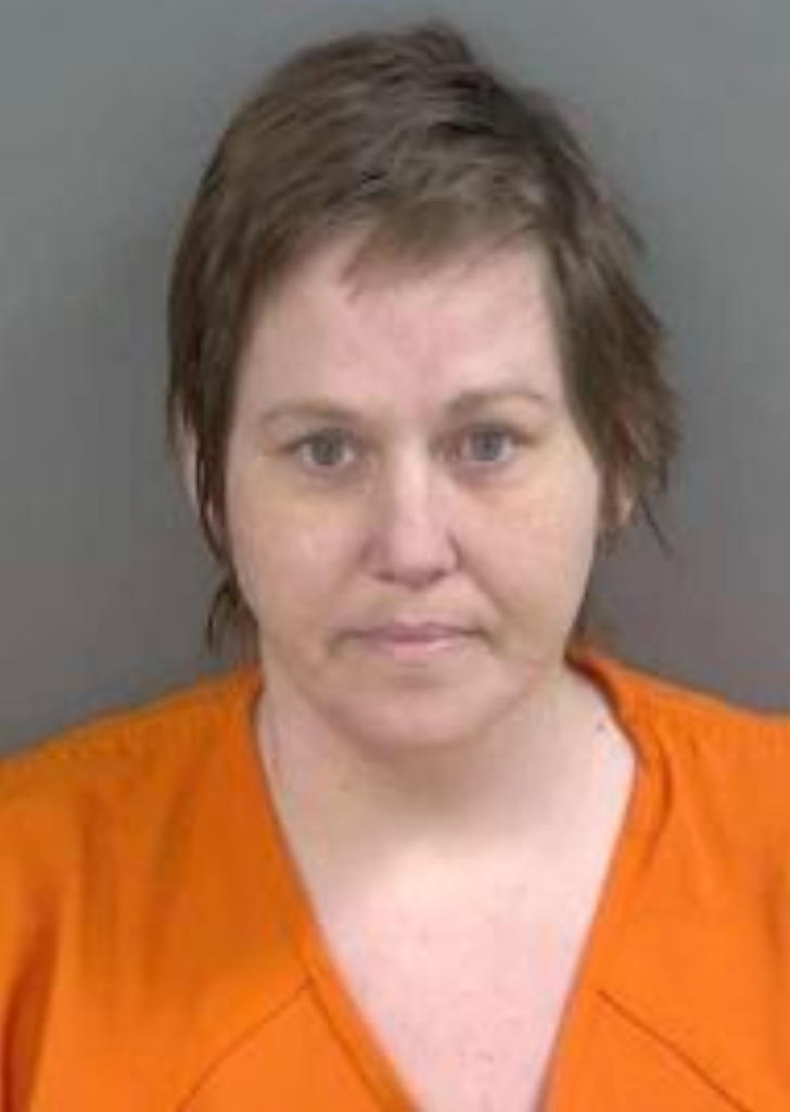 Mugshot of a woman with short brown hair, wearing an orange uniform.